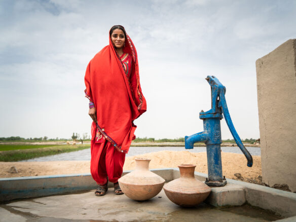 Sughra, 20, with a WaterAid installed water pump in the villlage of Muhammad Urs Sehejo in the Thatta District, Sindh Province, Pakistan.