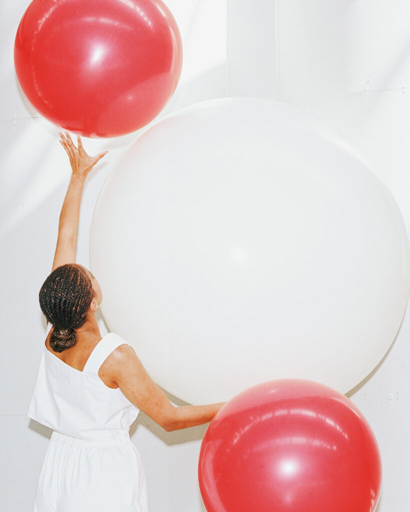 Woman holding one white and two red balls.